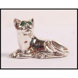 A sterling silver figurine in the form of a cat set with emerald eyes. Weight 10.6g. Measures 2cm