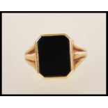 A stamped 585 14ct gold ring set with a square cut onyx panel to the head with reeded shoulders.