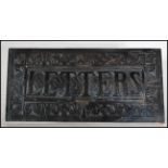 An early 20th Century Edwardian cast metal letter box, the frame of the letter box cast in relief