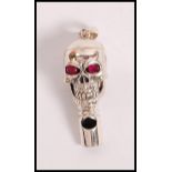 A stamped 925 silver whistle in the form of a skull set with ruby eyes. Weight 15.7g.