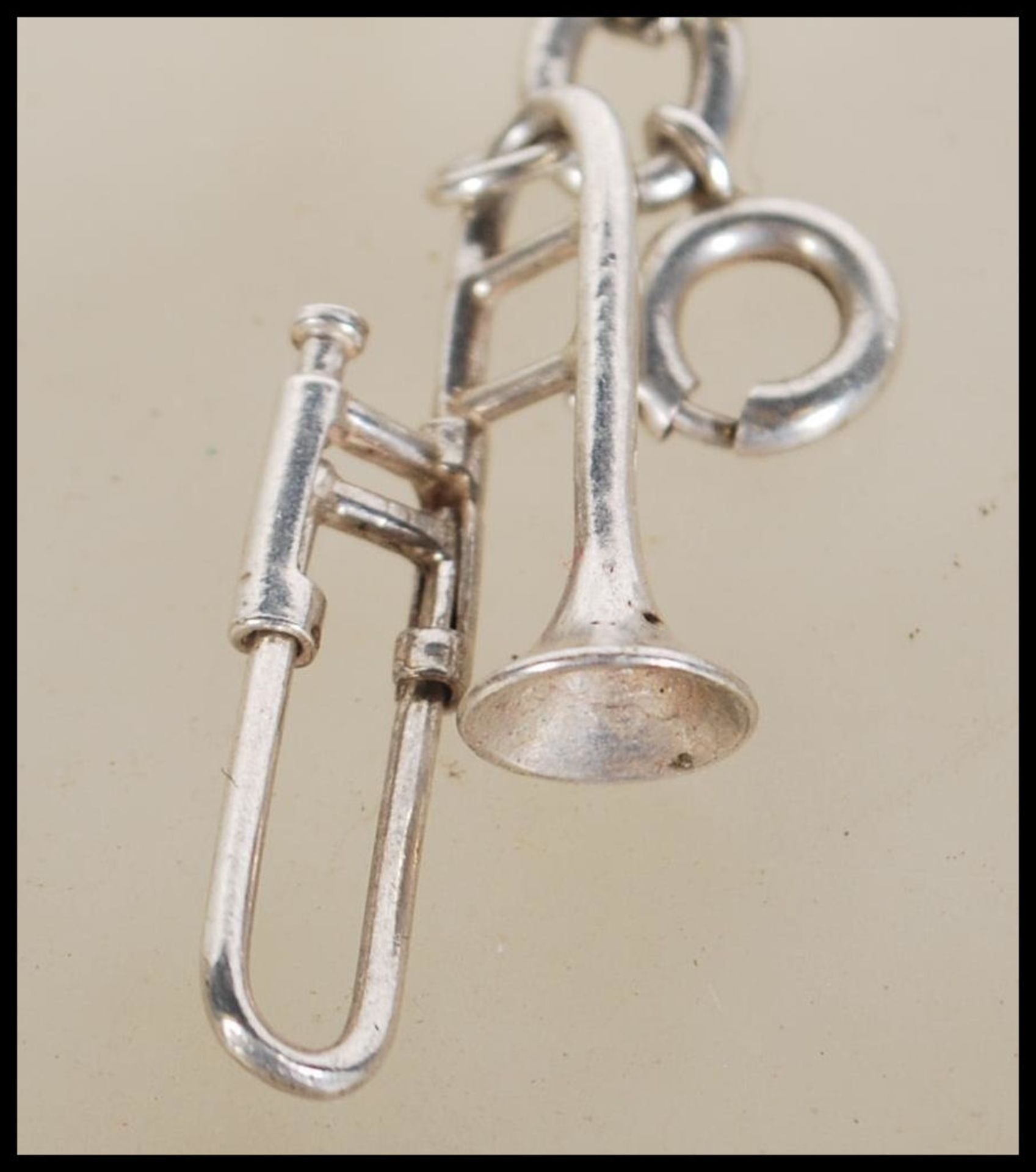 A silver charm bracelet having musical instrument charms to include trumpets, harp, bell violin, - Image 9 of 9