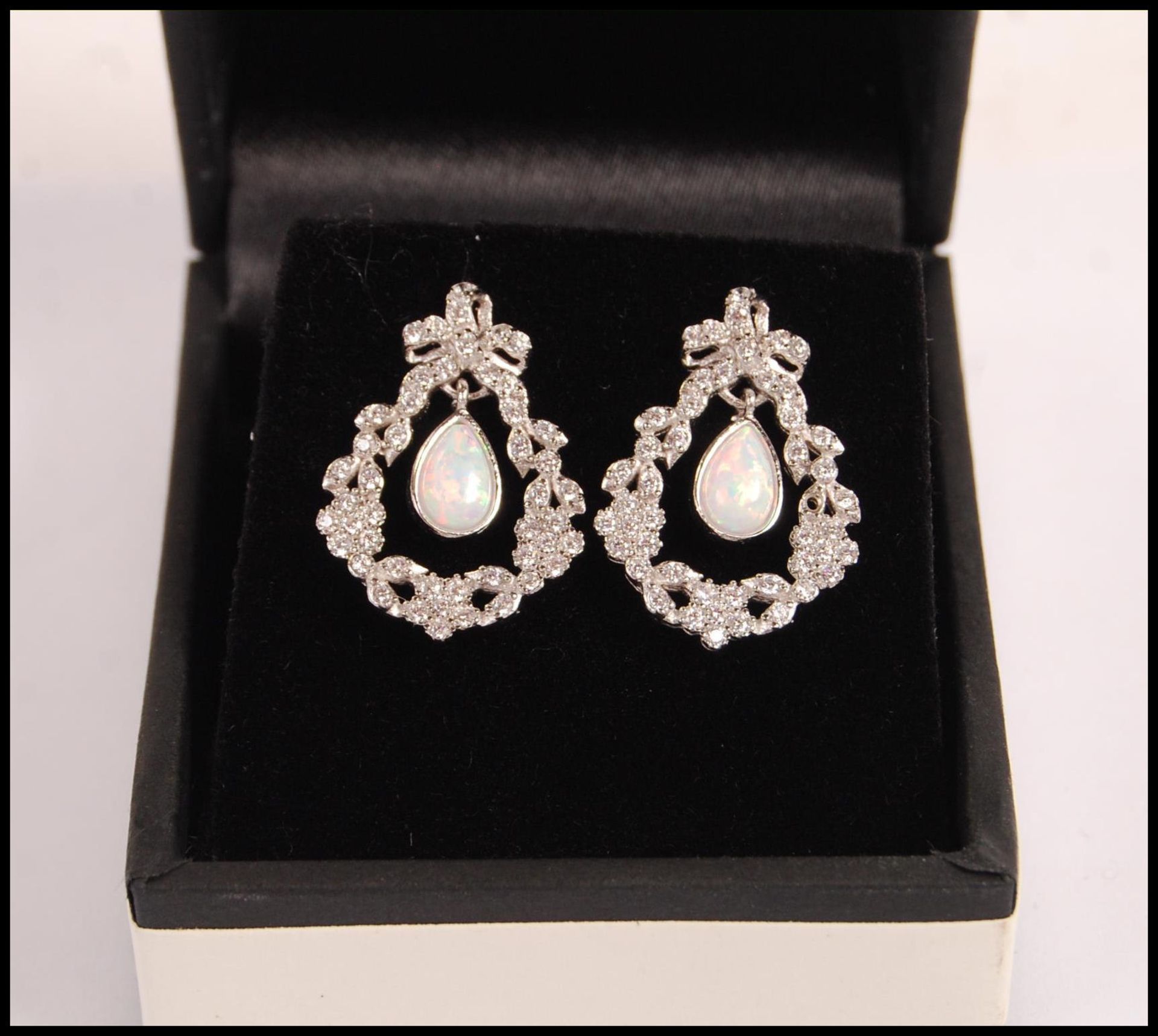 A pair of stamped 925 silver drop earrings set with pear shaped opalite panels, surrounded with