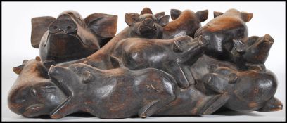 A carved hardwood figural group of a mother pig ( Sow ) with her drift of nine piglets.