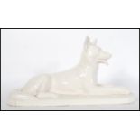 A large early 20th Century monochrome ceramic figurine of a German Shepherd / Alsatian in a seated