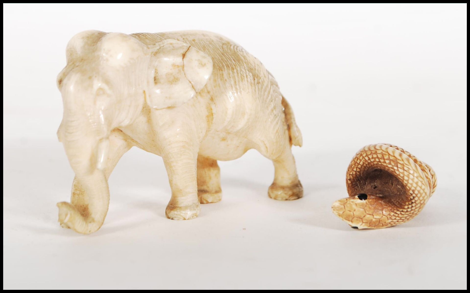 A good quality antique carved ivory figure of a elephant in a walking position. Together with a