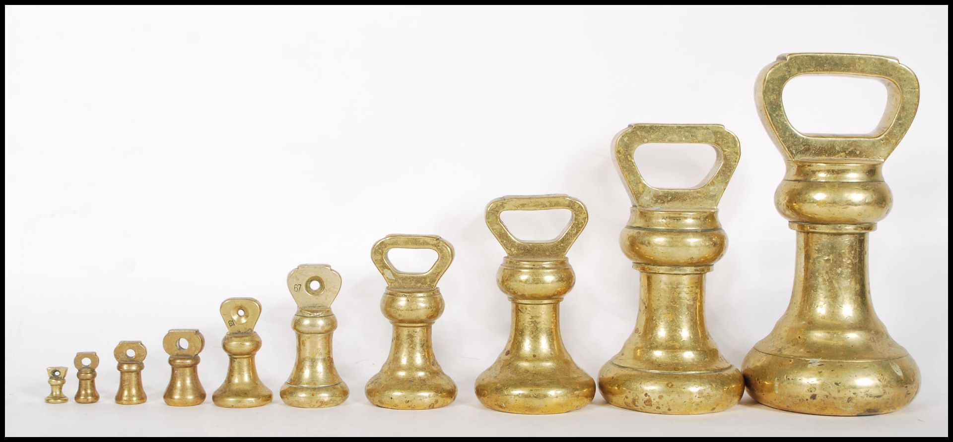 A selection of 20th century graduating brass bell weights having carrying handles atop, with the