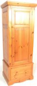 An antique style country pine sentry box wardrobe. Raised on a plinth base with short drawer