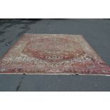 A vintage large hand woven floral rug carpet having red ground with beige geometric patterns and