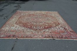 A vintage large hand woven floral rug carpet having red ground with beige geometric patterns and