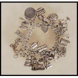 A silver hallmarked charm bracelet having heart padlock clasp with an assortment of silver charms to