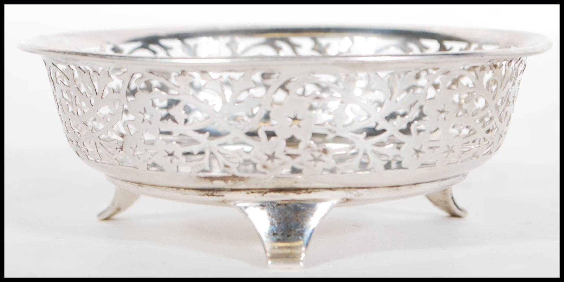 A early 20th Century silver hallmarked dish having pierced foliate decoration raised on three