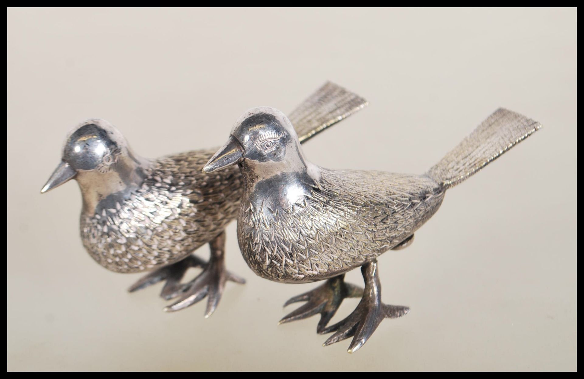 A pair of silver white metal salt and pepper condiments in the form of birds having engraved