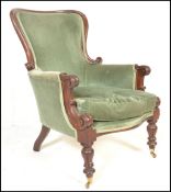 A Victorian mahogany library armchair being raised on turned legs with castors having green velour