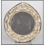 A sterling silver easel back photograph picture frame of circular form having rococo style relief