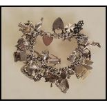 A vintage silver hallmarked charm bracelet having heart padlock clasp with an assortment silver