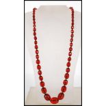 A cherry bakelite necklace having fiftyfive graduating oval faceted cut beads, with spring ring