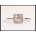 A stamped 18ct white gold ring set with a brilliant cut diamond in a square halo set with further