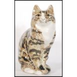 A vintage Winstanley ceramic tabby cat figurine modelled in a seated position having a brown mottled