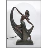 A 20th century Art Deco style table lamp in the form of semi-nude dancer in front of a oval