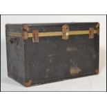 A large vintage travel trunk chest having metal brass style banding with leather carrying handles to