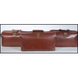 A collection of three vintage early to mid 20th Century Gladstone leather bags. Each having brass