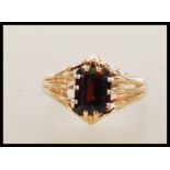 A hallmarked 9ct gold ring claw set with a rectangular cut red stone with reeded shoulders.