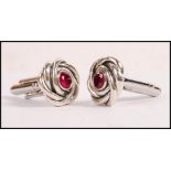 A pair of sterling silver knot design cufflinks set with central round cut rubies. Weight 12.8g.