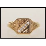 An unmarked 9ct gold signet ring having a square head having a row of white stones engraved with the