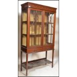 An Edwardian mahogany inlaid vitrine display cabinet being raised on square tapering legs with