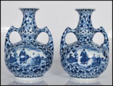 A matching pair of 20th Century Dutch twin handle vases having blue and white transfer printed