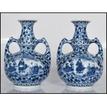 A matching pair of 20th Century Dutch twin handle vases having blue and white transfer printed
