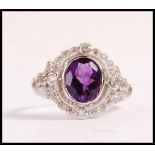 A stamped sterling silver ring set with an oval cut amethyst with a halo of CZ's. Weight 3.0g.