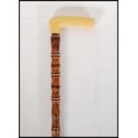 A 20th Century bone handle walking stick cane having turned wood decorated shaft. Measures 88cm