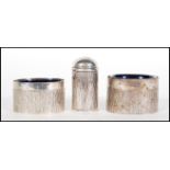 Two silver hallmarked table salts having bark effect decoration and blue glass liners, together with