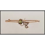 An early 20th Century stamped 9ct gold safety pin brooch having a floral design set with a peridot