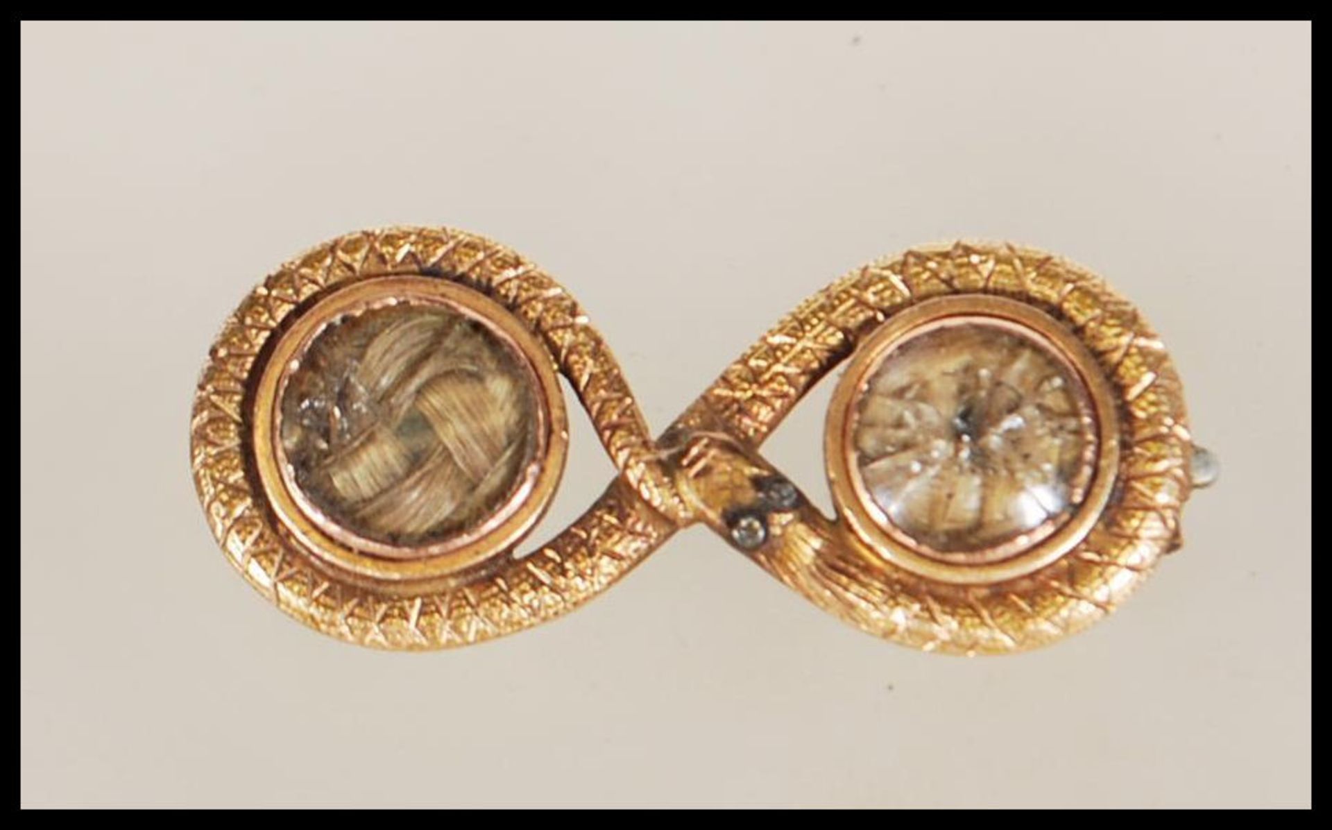 A 14ct gold textured snake mourning brooch with inset plaited hair under two glass windows,