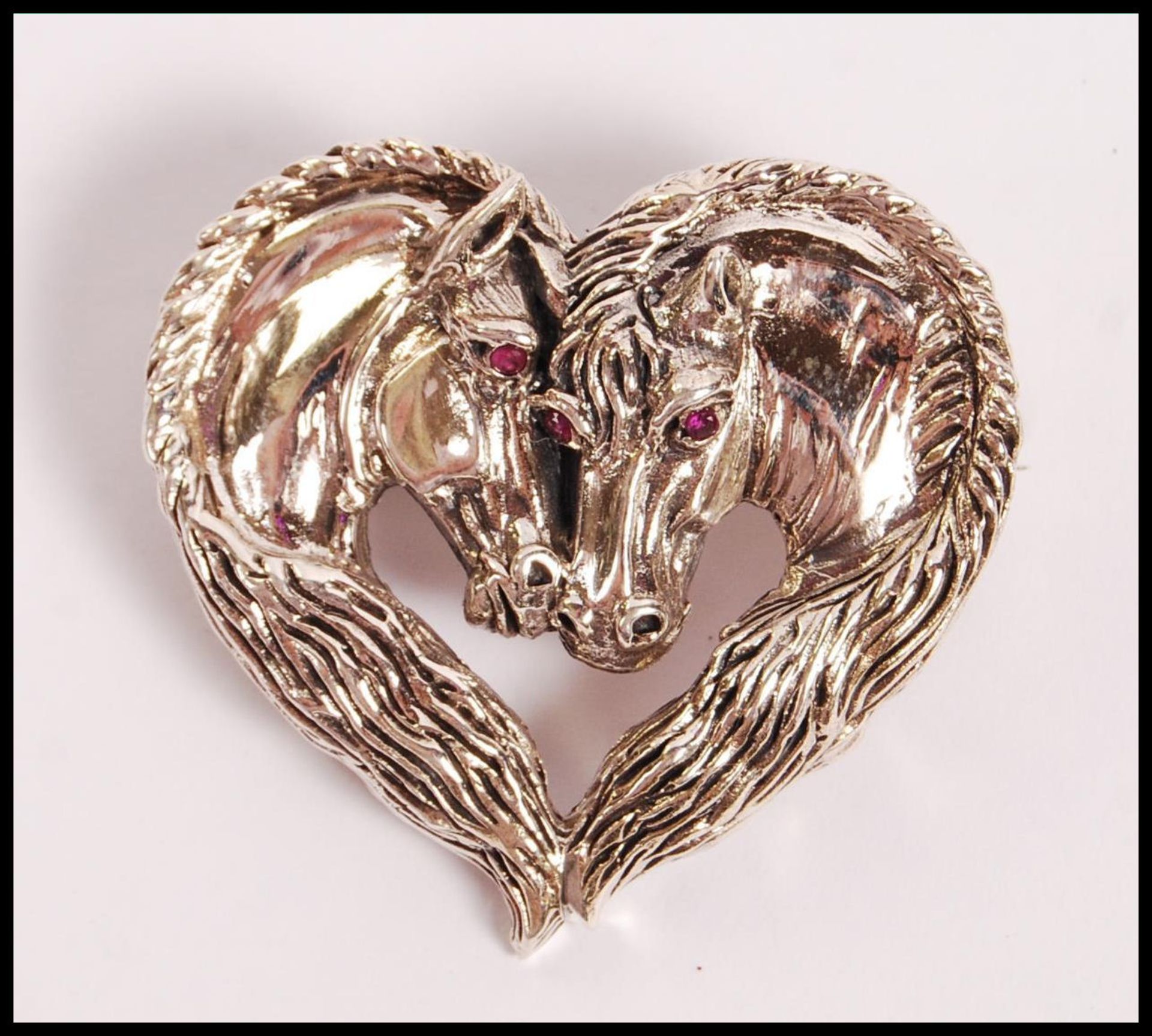 A stamped 925 silver heart shaped brooch in the form of two horses with red stone eyes. Weight 18.