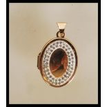 A stamped 375 9ct gold locket pendant of oval form set with a halo of white stones. Weight 2.0g.
