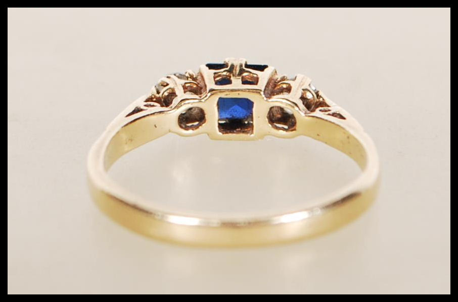 A hallmarked 9ct gold ring set with a square cut blue stone flanked by two round cut white stones. - Image 3 of 5