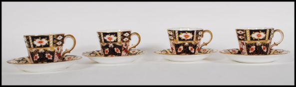 A set of four Royal Crown Derby Old Imari tea cups and saucers being hand painted in blue and red