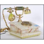 A vintage retro onyx and brass telephone having rotary dial to front, raised on a green stepped
