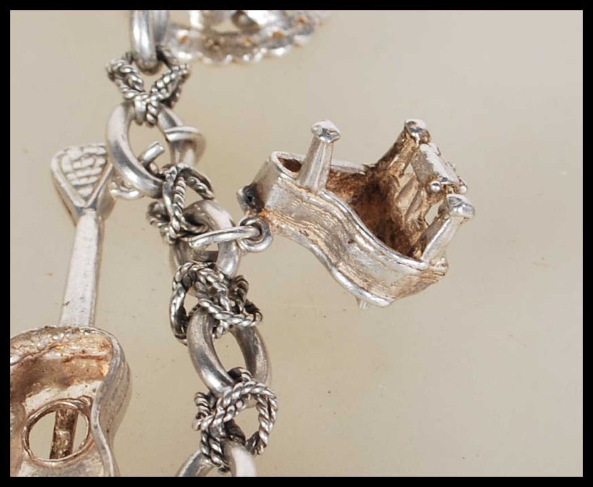 A silver charm bracelet having musical instrument charms to include trumpets, harp, bell violin, - Image 4 of 9