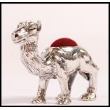 A small sterling silver pin cushion in the form of a camel having a red velvet cushion to the