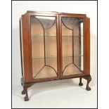 A 1930's Queen Anne revival mahogany china display cabinet being raised claw and ball feet with