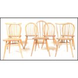 A harlequin set of mid century Ercol beech and elm wood dining chairs. Raised on turned legs