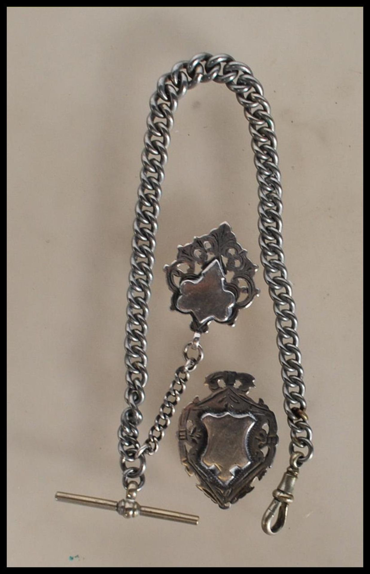 A white metal curb link fob chain having two silver hallmarked fob medals with unengraved panels.