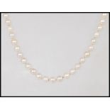 A single string cultured pearl necklace having a hallmarked 9ct yellow gold clap of decorative