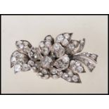 A mid 20th Century diamond flower brooch modelled with a central bloom having foliage behind, all