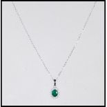 A stamped 18ct white gold necklace pendant having a central oval faceted cut emerald with a halo