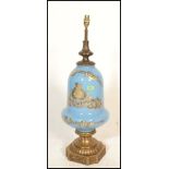 A large antique style bulbous blue glass and brass table lamp. Of Neo classical design on blue
